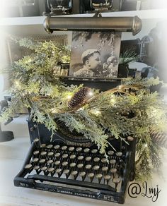 an old - fashioned typewriter decorated with pine cones and greenery