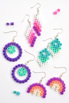 four pairs of earrings made out of legos on a white surface with beads and other items