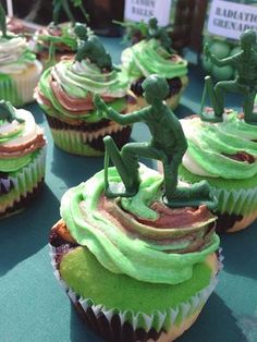 cupcakes with green frosting and figurines on them are sitting on a table