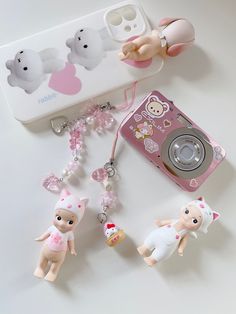 a cell phone and some little dolls on a table next to a case with a camera