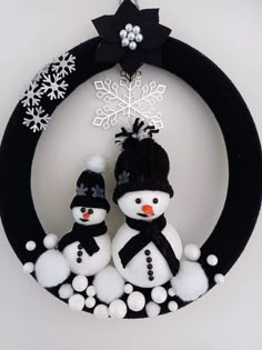 two snowmen sitting on top of a black wreath