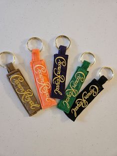 four keychains with different designs on them sitting next to each other in the shape of a bottle opener