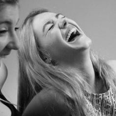 two girls are laughing and looking at each other