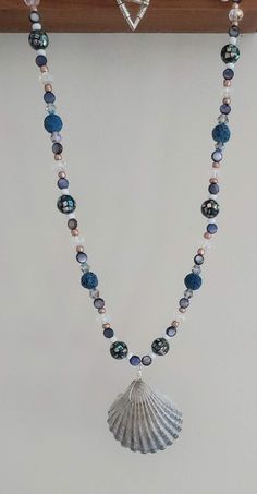 This necklace is made with navy lava beads, natural shell beads, gold seed beads, clear rondelles, multi-color bicone crystal beads, speckled beads, and a scallop shell in the middle. Toggle clasp. Measures 21 inches long end to end. Beaded Shell, Seashell Jewelry, Scallop Shell, Ocean Jewelry, Lava Beads, Scallop Shells, Seashell Crafts, Lava Bead, Shell Necklace