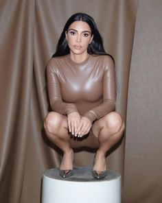 a woman sitting on top of a white stool