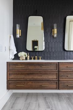 a bathroom vanity with two mirrors above it and a vase on the counter next to it