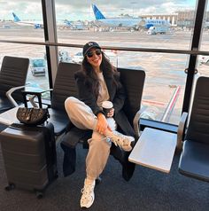 a woman is sitting in an airport waiting for her plane to take off and drinking coffee