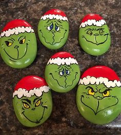 six grin face rocks with santa hats on them