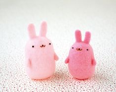 two pink and one white bunny dolls sitting next to each other