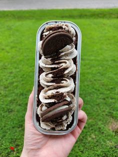 an ice cream sundae with cookies and oreo slices in a container on the grass