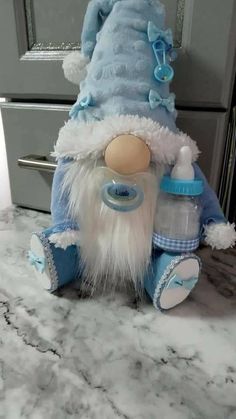 a stuffed animal that is wearing a blue outfit and holding a bottle in it's hand