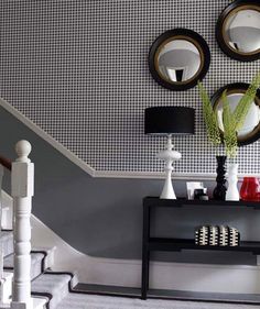 a black and white table with two vases on it next to a stair case