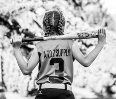 a woman holding a baseball bat over her shoulder and wearing a jersey with the number 2 on it