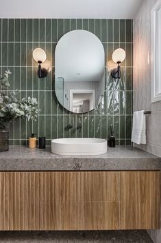 a bathroom with a sink, mirror and plants on the counter in front of it