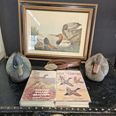 two books are sitting on a table next to an old duck book and other items