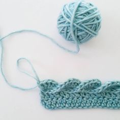 two balls of yarn next to each other on a white surface with one ball of yarn in the foreground