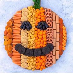 a pumpkin made out of corn, carrots and crackers with a face painted on it