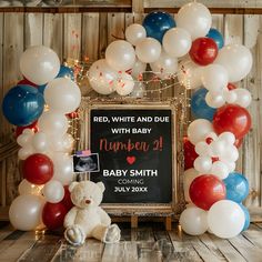 a teddy bear sitting in front of a baby sign surrounded by balloons