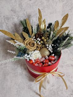 a red box filled with lots of candy covered in gold and white flowers on top of a table