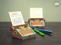 a desk with two miniature typewriters on top of it and some pens next to them