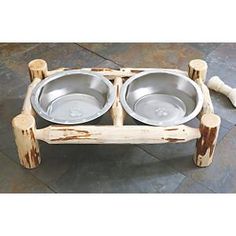 two bowls sit on a wooden stand with bone handles and legs, ready to be used as a pet bowl