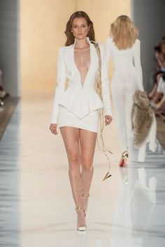 a model walks down the runway in a white outfit