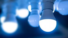 many light bulbs are lit up in the dark room with blue lights around them and one bulb is turned on