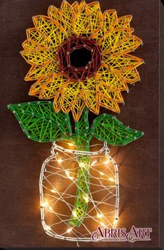 a string art sunflower in a mason jar with fairy lights on the outside and inside