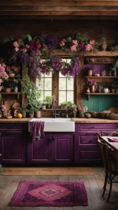 a kitchen with purple cabinets and lots of flowers on the counter top, along with a rug