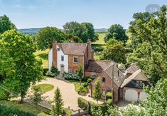 an aerial view of a large brick house surrounded by trees and greenery in the countryside