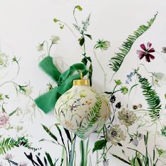 a white ornament with green ribbon and flowers on the wall next to it