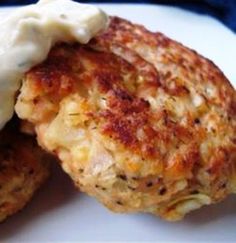 two crab cakes on a white plate with butter and dill pickle garnish