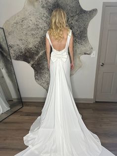 a woman standing in front of a mirror wearing a white dress