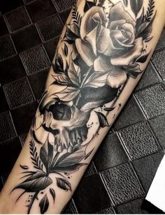 a skull and roses tattoo on the arm