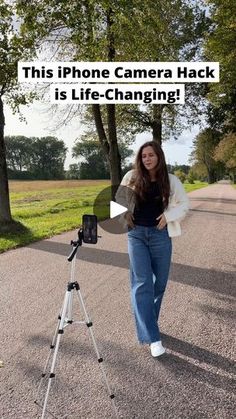 a woman is walking down the street with her camera on a tripod and texting, this iphone camera hack is life - changing