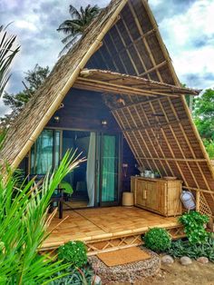 a small house made out of bamboo with a thatched roof and wooden flooring