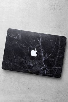 an apple laptop computer sitting on top of a white table next to a gray wall