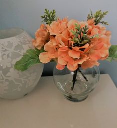 there is a vase with flowers in it on the table next to another vase that has an orange flower