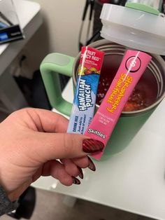 a person holding two tubes of toothpaste in front of a bowl of soup