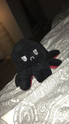 a black stuffed animal sitting on top of a bed