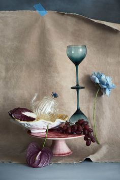 two wine glasses and grapes sit on a cake plate