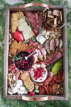 a wooden box filled with lots of different types of food and crackers on top of it