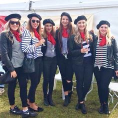 a group of women standing next to each other in front of a tent wearing hats and scarves