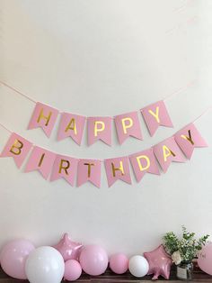 a birthday party with pink and white balloons, streamers and stars on the mantle