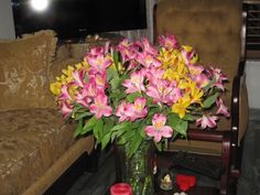 a vase filled with pink and yellow flowers on top of a table next to a couch