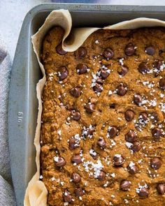 a pan filled with chocolate chip cookie bars on top of a table next to a cup of coffee