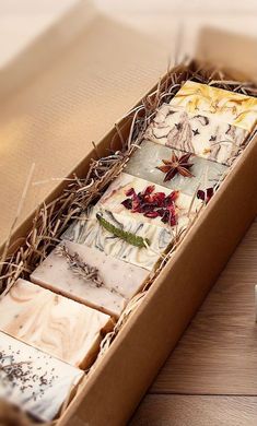 a box filled with different types of soaps on top of a wooden table next to a cup