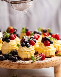 cupcakes with fresh berries and mint sprinkles on a wooden platter