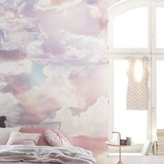 the bedroom is decorated in pastel colors and has a large window that looks out onto the sky