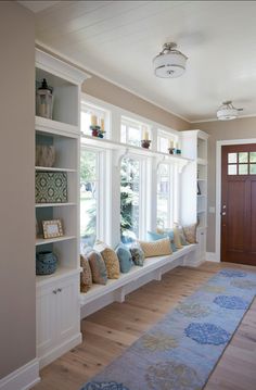 a room filled with lots of windows next to a wooden door and white shelves on the wall